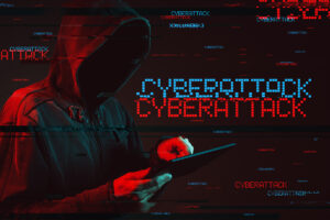 A man in a black hoodie using a tablet for a cyberattack.