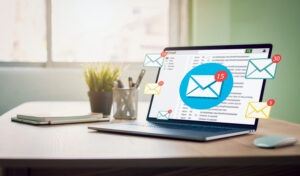 An open laptop with an email client on it and new message icons surrounding it.